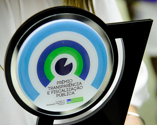 Prêmio Transparência e Fiscalização Pública 2014 Imagem da placa comemorativa do Prêmio Transparência e Fiscalização Pública 2014, com círculos concêntricos azul-claro, branco, azul-escuro e verde.