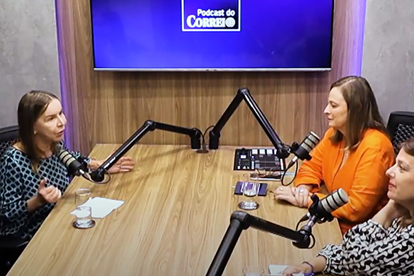 Dra. Lúcia Willadino Braga conversando com as jornalistas Denise Rothenburg e Ana Maria Campos durante gravação do Podcast do Correio (Captura de imagem – crédito: Correio Braziliense) À esquerda e sentada, Dra. Lúcia Willadino Braga, vestindo blusa xadrez preta e branca, fala ao microfone. À direita, as jornalistas Denise Rothenburg, de blusa laranja, e Ana Maria Campos, de blusa com detalhes pretos e brancos, escutam.