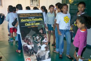 Crianças do Centro de Convivência Mozart Parada junto ao cartaz da apresentação Do lado de fora do Teatro SARAH, crianças do Centro de Convivência Mozart Parada porganizam-se em fila para assistir ao ensaio da Orquestra Sinfônica do Teatro Nacional Cláudio Santoro.