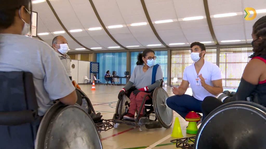 Rugby em cadeira de rodas Na quadra poliesportiva do SARAH Lago Norte, professor de educação física, sentado, dá aula de rugby a paratletas, sentados em cadeiras de rodas.