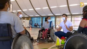 Rugby em cadeira de rodas Na quadra poliesportiva do SARAH Lago Norte, professor de educação física, sentado, dá aula de rugby a paratletas, sentados em cadeiras de rodas.