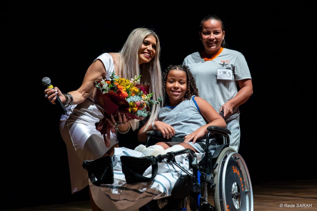 A paciente Jade Emanuelly Marques entregando um buquê de flores a Adryana Ribeiro.